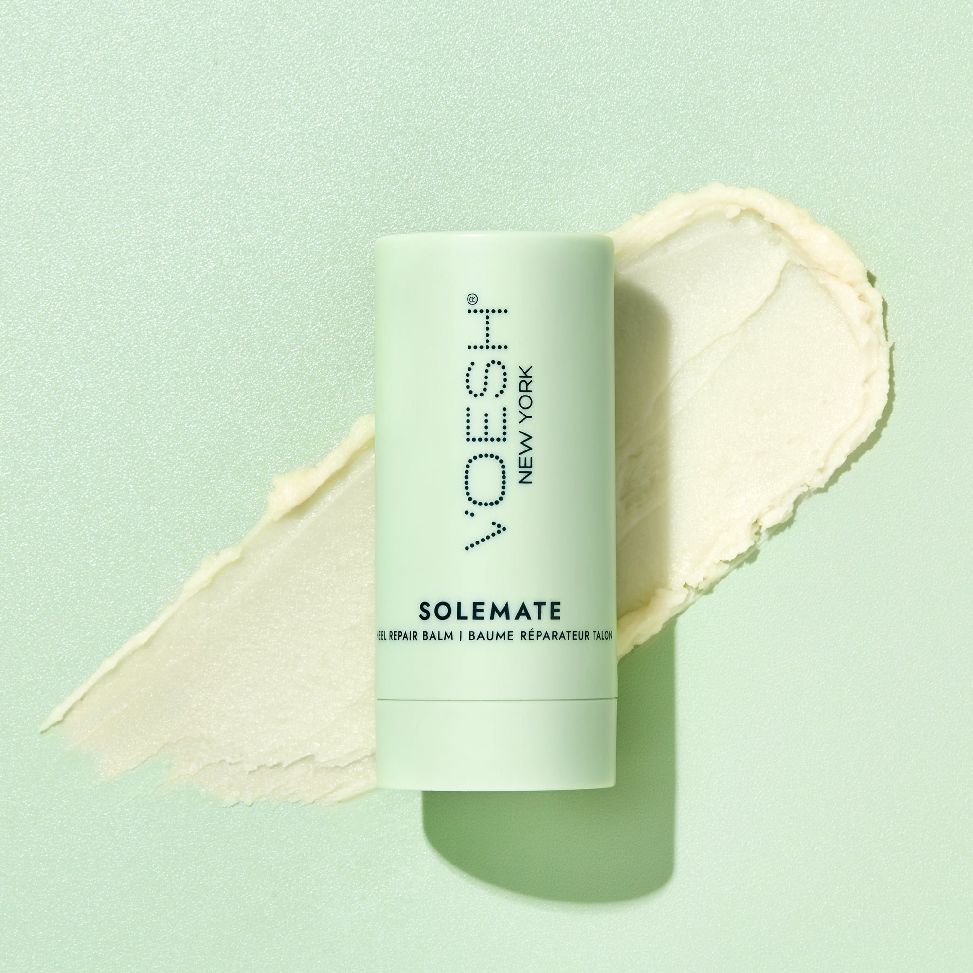 Solemate Heel Repair Balm pictured on top of its balm texture on a green background.